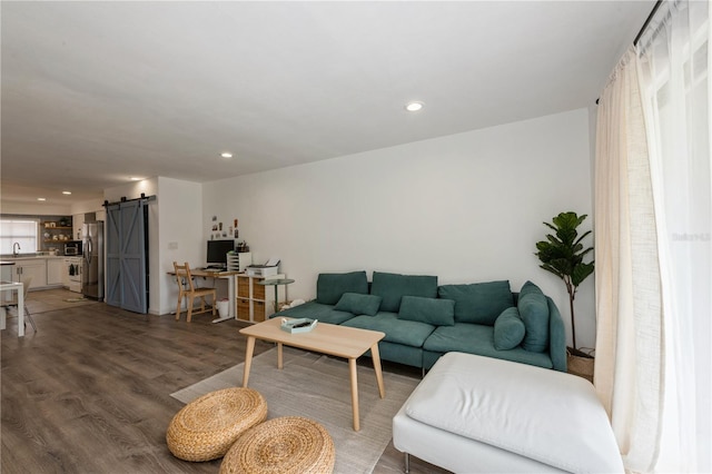 living room with a barn door, recessed lighting, and light wood-style floors