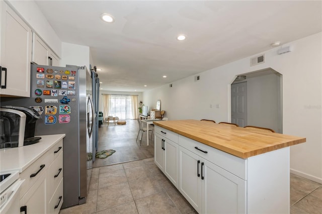 kitchen featuring recessed lighting, arched walkways, white cabinets, wooden counters, and visible vents