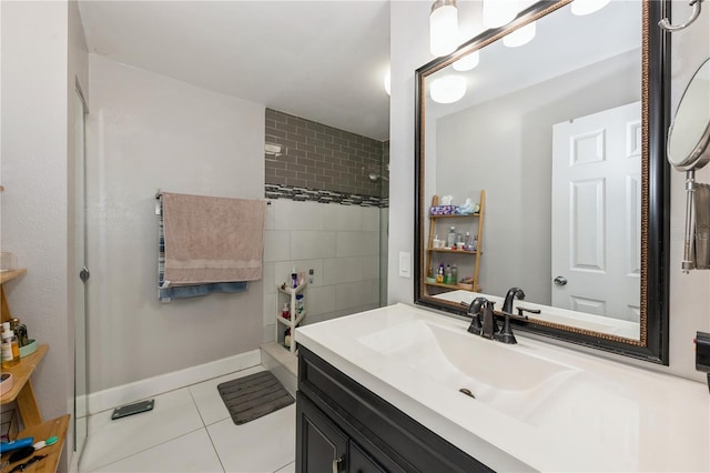 full bath with tile patterned flooring, tiled shower, vanity, and baseboards