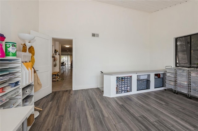 interior space with a high ceiling, visible vents, wood finished floors, and baseboards