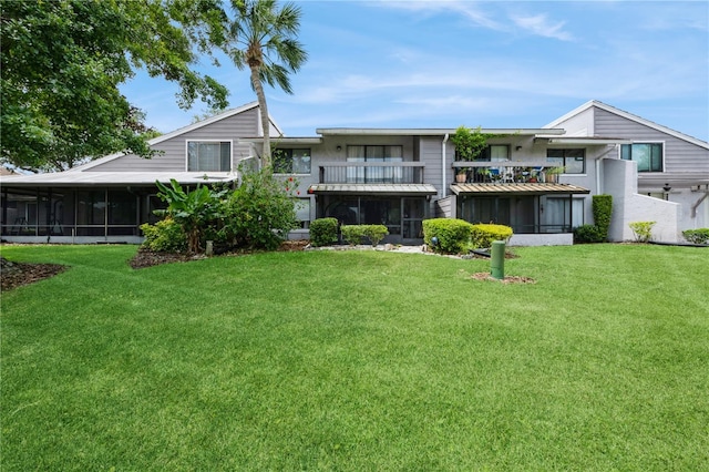 rear view of property with a balcony, a sunroom, and a lawn