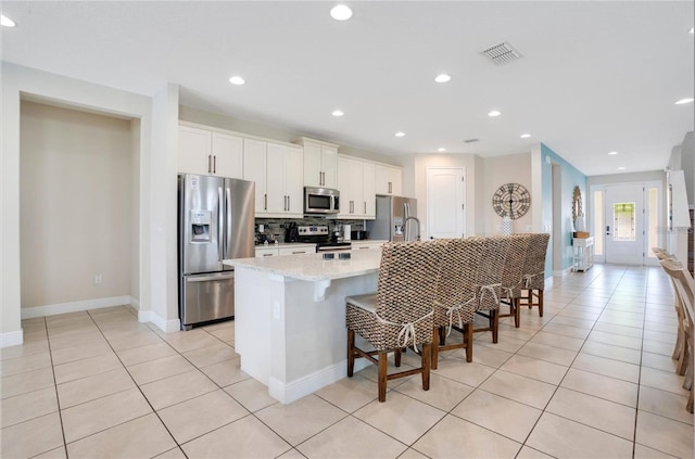 kitchen with visible vents, light tile patterned floors, a breakfast bar, and stainless steel appliances