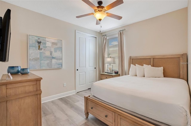 bedroom with a closet, baseboards, a ceiling fan, and light wood finished floors
