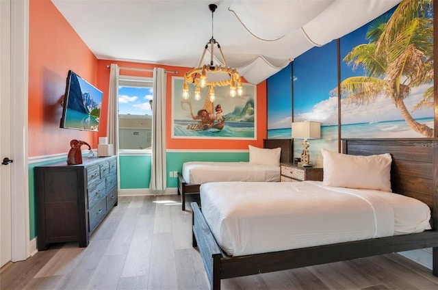 bedroom featuring baseboards, light wood finished floors, and a notable chandelier