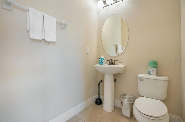half bath featuring tile patterned flooring, a sink, baseboards, and toilet