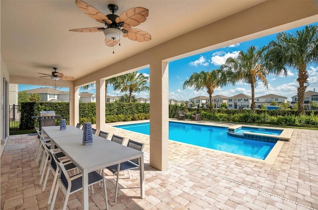 view of pool featuring fence, outdoor dining space, a pool with connected hot tub, ceiling fan, and a patio area