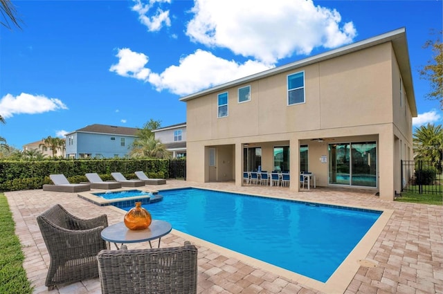 view of swimming pool with a pool with connected hot tub, fence, and a patio area