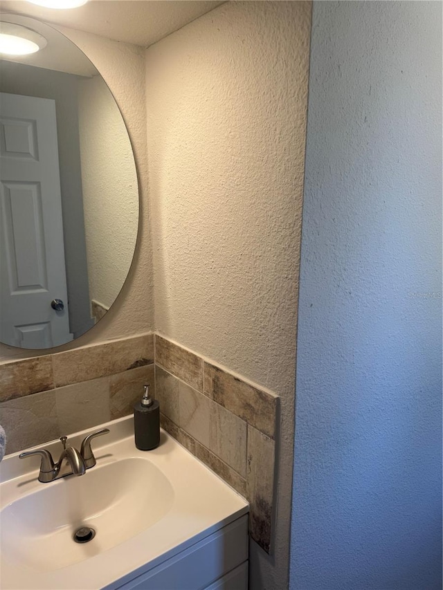 9400 SE 119th St, Belleview, FL 34420 - bathroom with backsplash, a textured wall, vanity, and tile walls