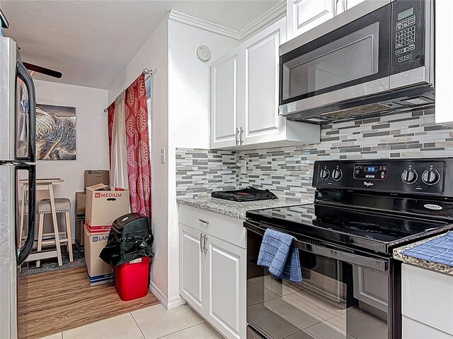 741 Hillview Dr, Altamonte Springs, FL 32714 - kitchen with stainless steel microwave, light tile patterned flooring, backsplash, black electric range, and white cabinets