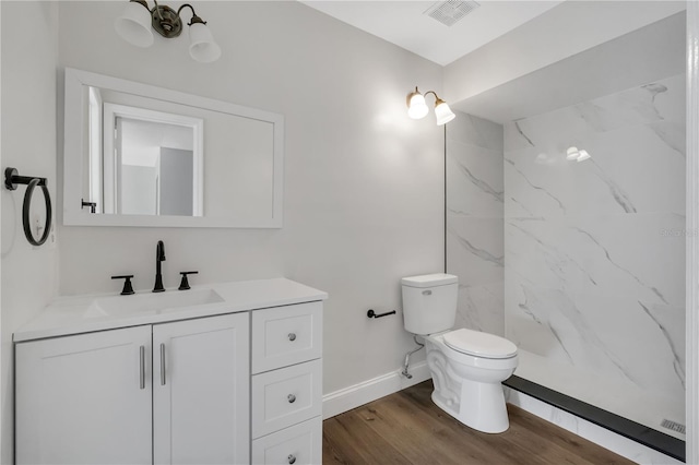 bathroom featuring visible vents, wood finished floors, vanity, baseboards, and toilet