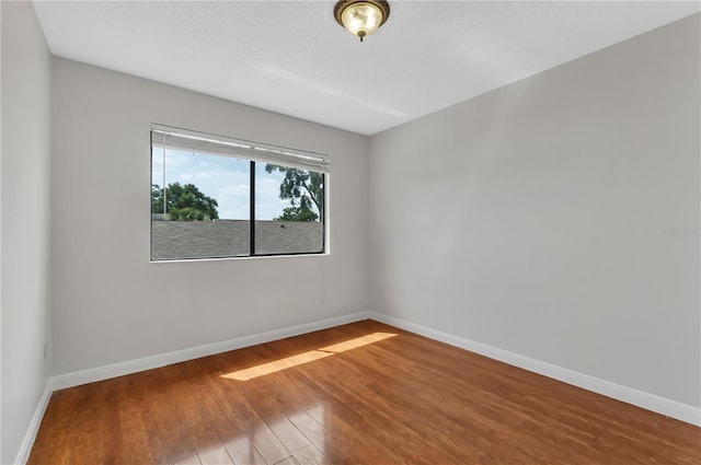 empty room with baseboards and wood finished floors