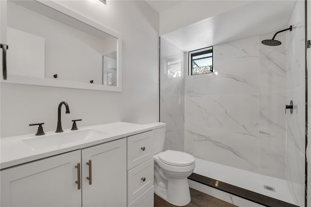 full bath with wood finished floors, toilet, a marble finish shower, and vanity