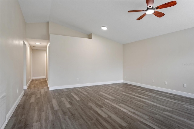 spare room featuring lofted ceiling, dark wood-style flooring, ceiling fan, and baseboards