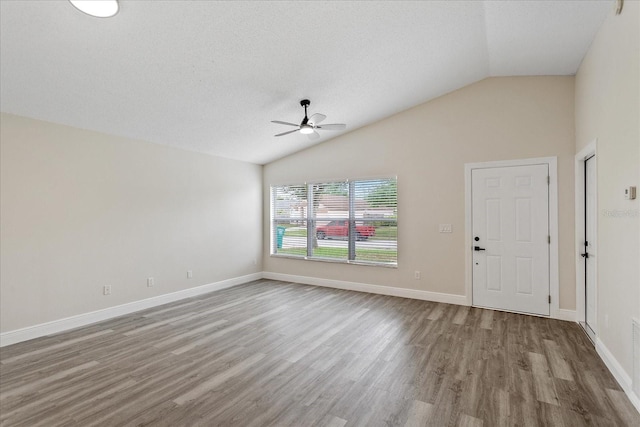 unfurnished living room with ceiling fan, wood finished floors, lofted ceiling, and baseboards