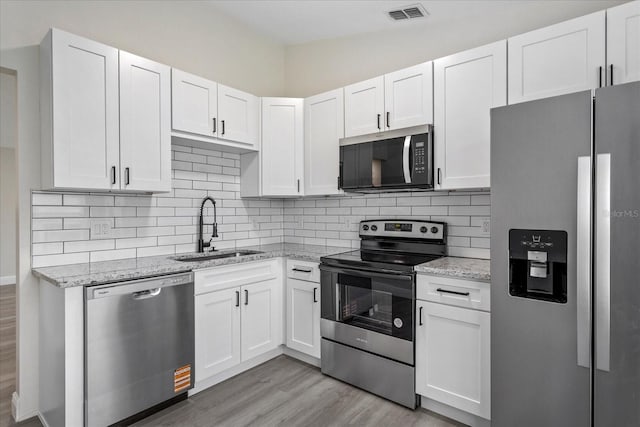 kitchen featuring white cabinetry, light wood-style flooring, a sink, appliances with stainless steel finishes, and visible vents