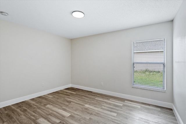 spare room featuring baseboards and wood finished floors