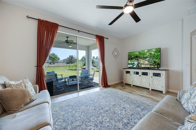 living area featuring plenty of natural light, wood finished floors, baseboards, and ceiling fan