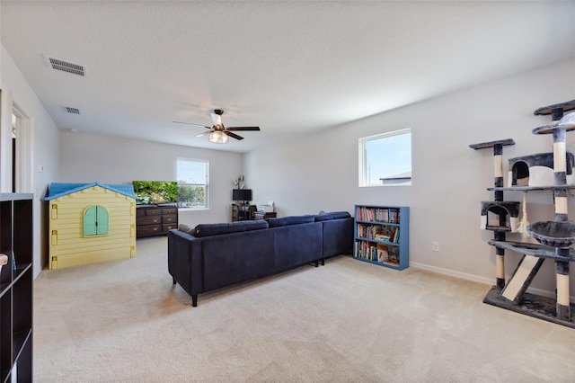 carpeted living area featuring baseboards, a ceiling fan, and visible vents