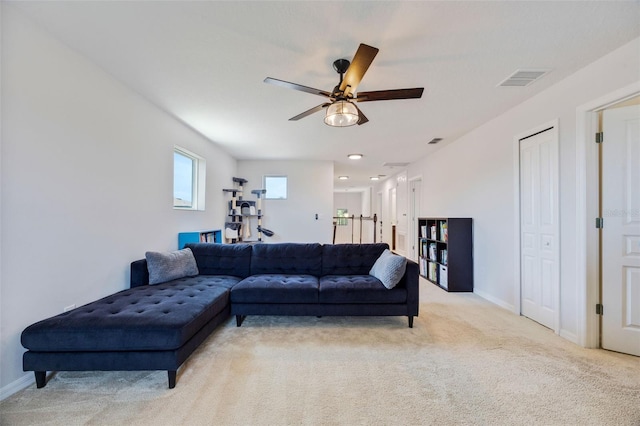 living area with light colored carpet, ceiling fan, baseboards, and visible vents
