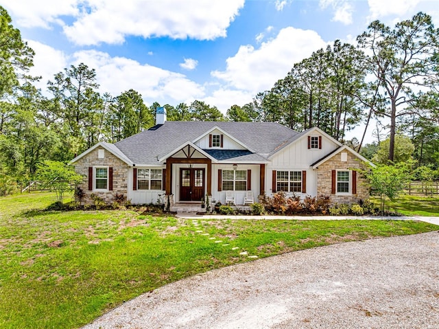 42368 W Cashew Ct, Eustis, FL 32736 - view of front facade with a chimney, board and batten siding, a front yard, and stone siding