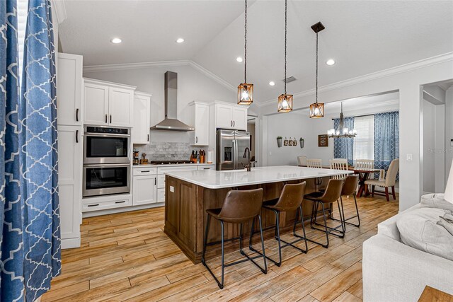 42368 W Cashew Ct, Eustis, FL 32736 - kitchen with white cabinets, stainless steel appliances, ornamental molding, and wall chimney exhaust hood