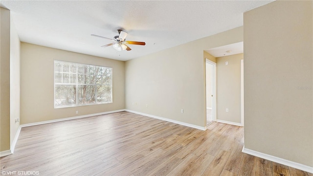 spare room featuring baseboards, ceiling fan, and light wood-type flooring