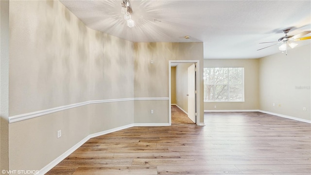 spare room featuring a ceiling fan, baseboards, and wood finished floors