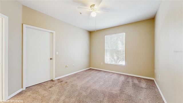 spare room with carpet floors, baseboards, and a ceiling fan