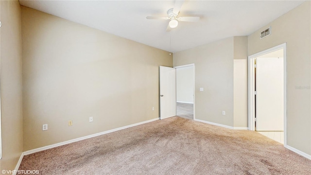 empty room with baseboards, ceiling fan, carpet, and visible vents