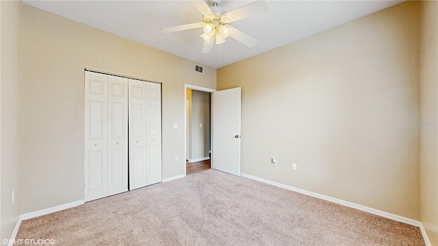 unfurnished bedroom featuring ceiling fan, visible vents, baseboards, a closet, and carpet