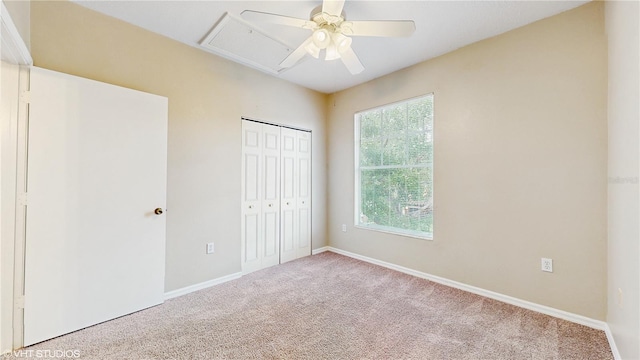 unfurnished bedroom with carpet flooring, ceiling fan, attic access, baseboards, and a closet
