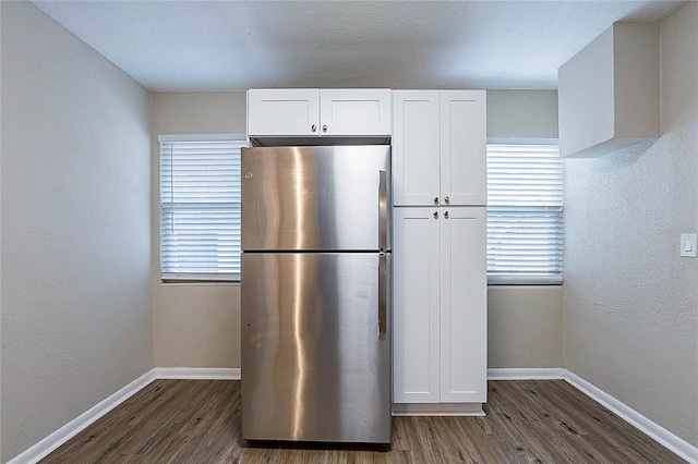 kitchen featuring freestanding refrigerator, dark wood-style flooring, baseboards, and white cabinets