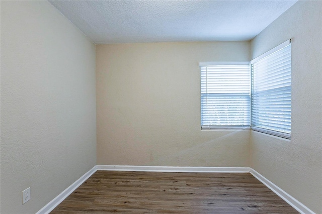 spare room with baseboards, wood finished floors, and a wealth of natural light