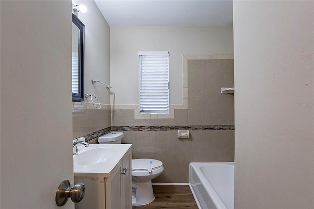 full bathroom with tile walls, wood finished floors, vanity, a wainscoted wall, and toilet