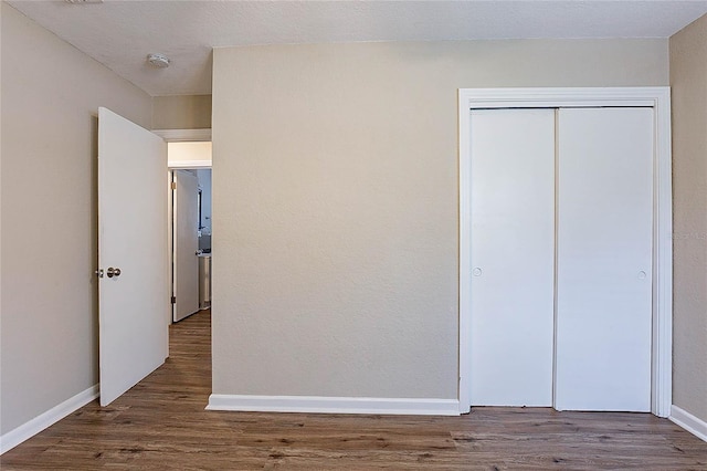 unfurnished bedroom with baseboards, wood finished floors, and a closet