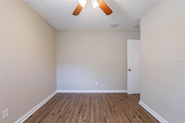spare room featuring a ceiling fan, baseboards, visible vents, and wood finished floors
