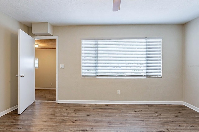 empty room with baseboards, wood finished floors, and a wealth of natural light