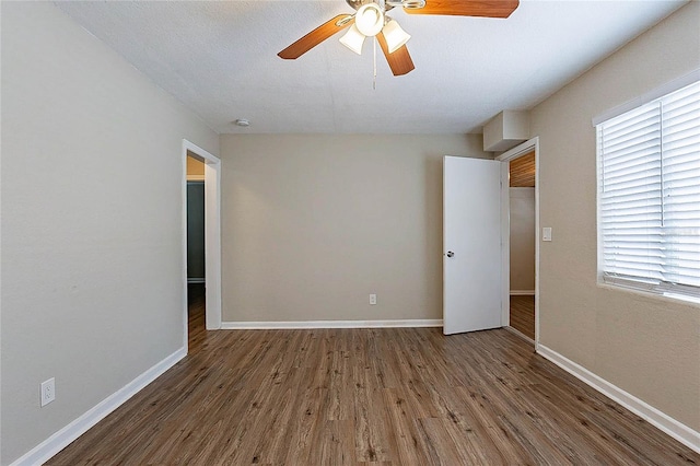 empty room featuring baseboards, a ceiling fan, and wood finished floors