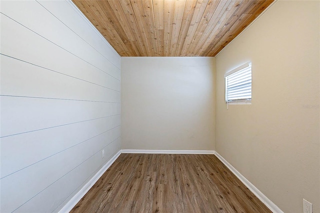 empty room with baseboards, wooden ceiling, and wood finished floors