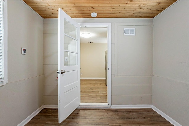 doorway with visible vents, baseboards, wood ceiling, and wood finished floors