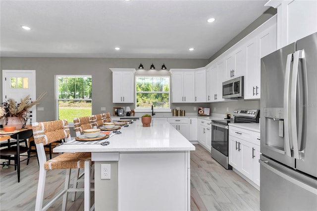 6725 SW 131st Cir, Ocala, FL 34481 - kitchen featuring a kitchen breakfast bar, a kitchen island, stainless steel appliances, and a wealth of natural light