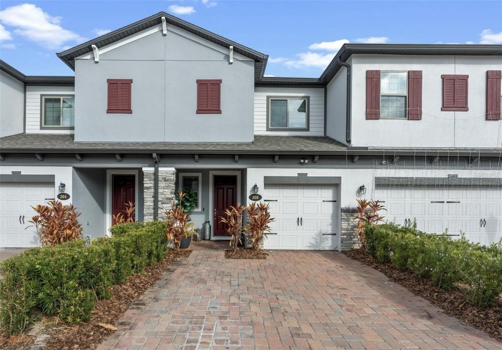 308 Rustic Loop, Sanford, FL 32771 - townhome / multi-family property with a garage, stone siding, stucco siding, and decorative driveway