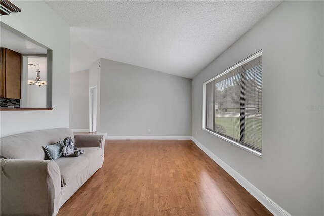 819 Haulover Dr, Altamonte Springs, FL 32714 - living area featuring light wood-style floors, a chandelier, a textured ceiling, baseboards, and vaulted ceiling