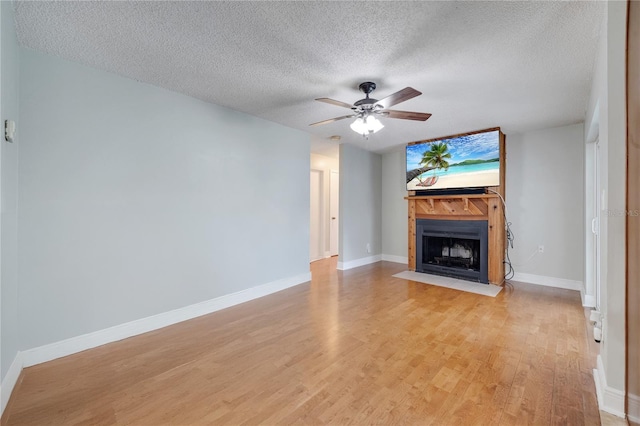 819 Haulover Dr, Altamonte Springs, FL 32714 - unfurnished living room with a fireplace with flush hearth, light wood finished floors, a textured ceiling, ceiling fan, and baseboards