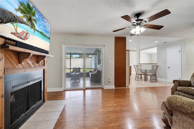 819 Haulover Dr, Altamonte Springs, FL 32714 - living area with light wood-style flooring, a textured ceiling, a fireplace, baseboards, and a ceiling fan