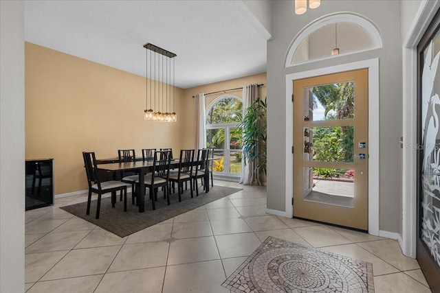 foyer featuring light tile patterned flooring, an inviting chandelier, and baseboards