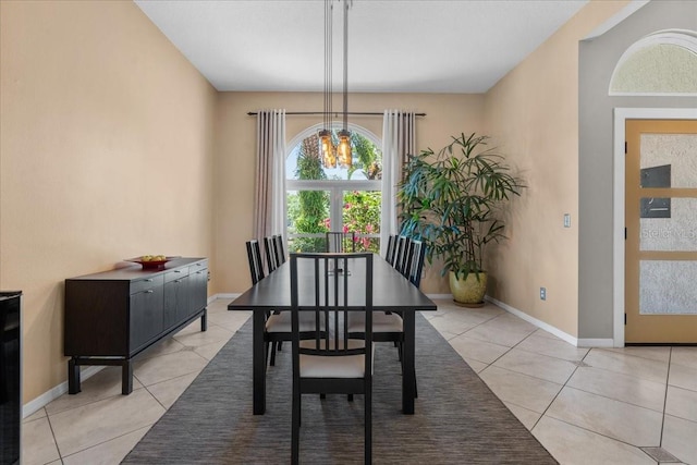 dining area featuring light tile patterned floors, a notable chandelier, and baseboards