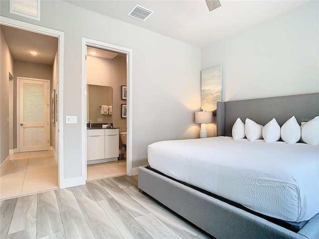 7770 Sandy Ridge Dr Unit 139, Reunion, FL 34747 - bedroom with baseboards, ensuite bath, visible vents, and light wood-style flooring