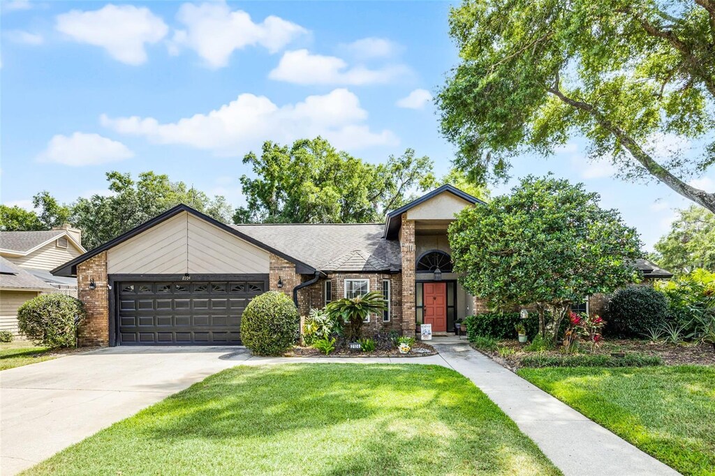 2104 Palm Crest Dr, Apopka, FL 32712 - view of front of property with a garage, brick siding, a front lawn, and driveway