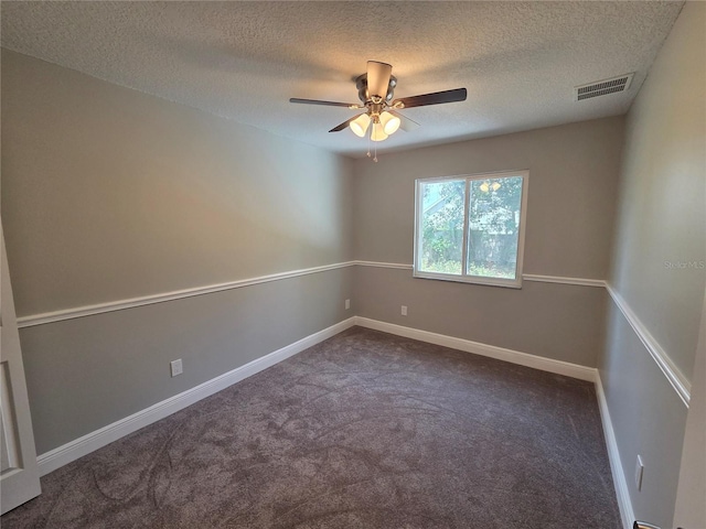 unfurnished room with a ceiling fan, visible vents, dark carpet, and a textured ceiling